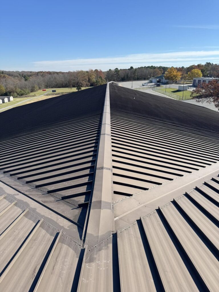 Standing seam metal roof ridge installation by J Cole Roofing & Construction in Austin AR