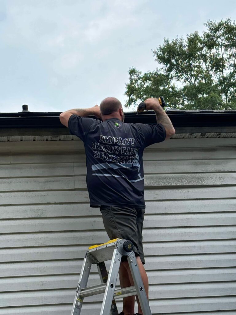 Roofing contractor inspecting gutter and roof edge by J Cole Roofing & Construction in Austin AR
