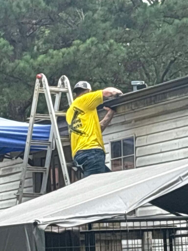 Roofing contractor working on gutter and roof edge by J Cole Roofing & Construction in Austin AR